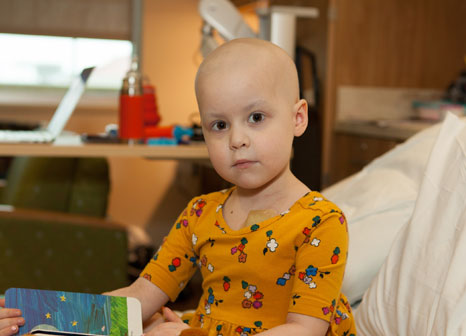 little girl sitting on hospital bed